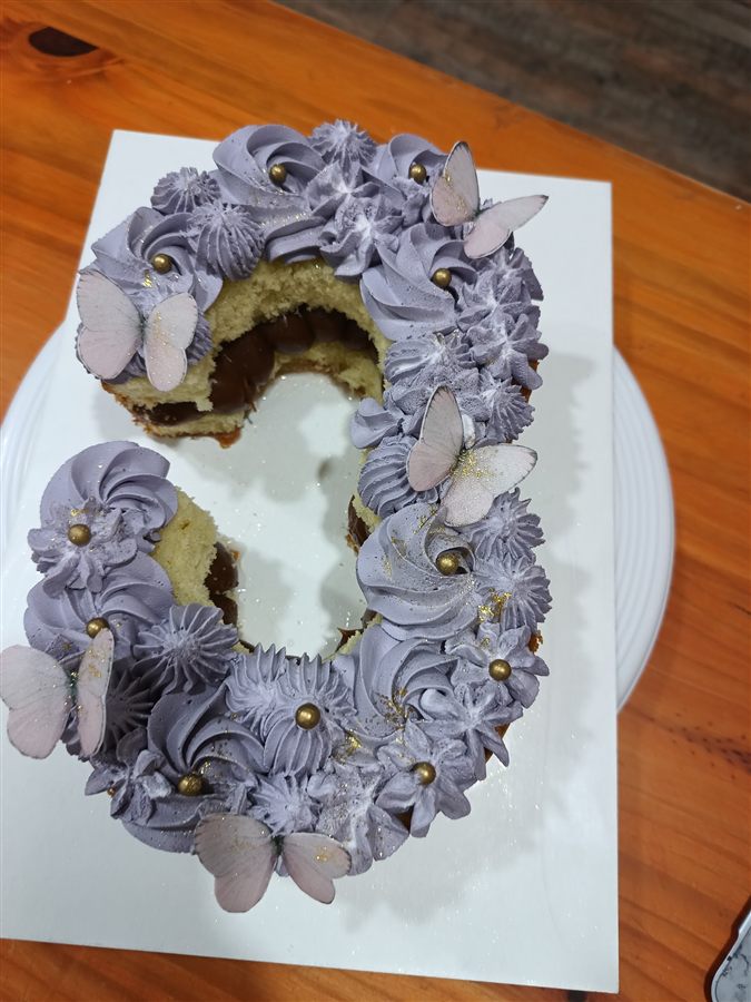 Torta con el número 3 en crema lila, mariposas de azúcar y detalles en pan de oro.