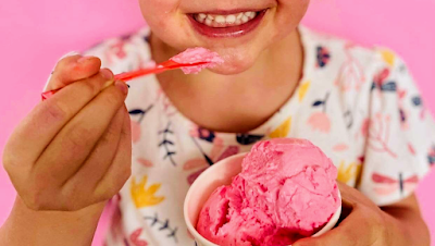 A customer smiling and enjoying a scoop of bright pink gelato at Favourite Flavours