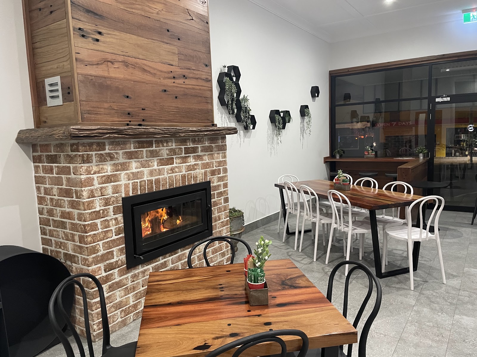 Foxy's Bakery interior with a lit brick fireplace, reclaimed-timber tables and bentwood chairs