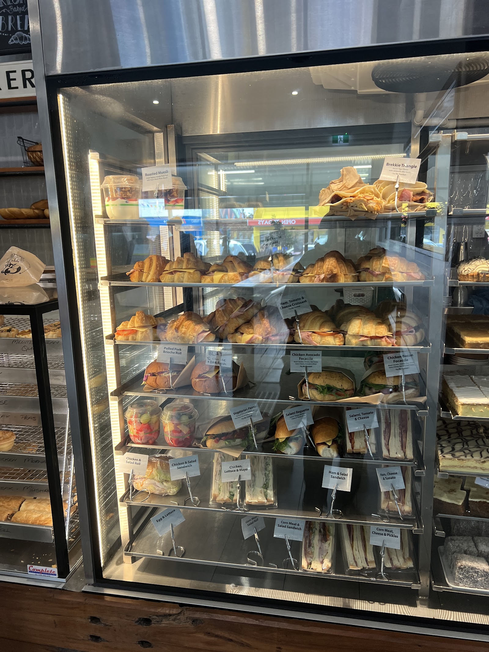 Bakery display cabinet full of croissants, pies, sausage rolls and sandwiches
