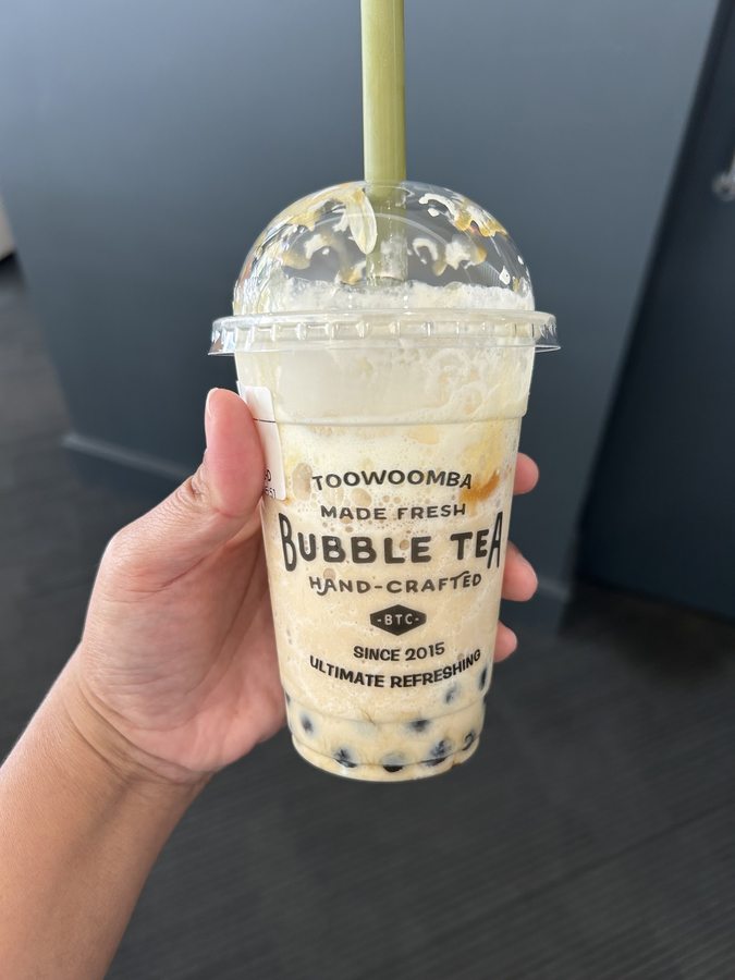 Close-up of a hand-held Bubble Tea City cup of milk tea with tapioca pearls
