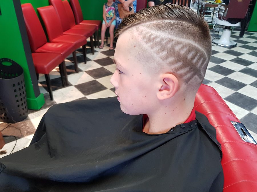 A sharp fade with a hair-art design on a young customer