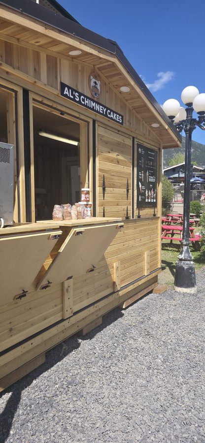 AL's Chimney Cakes cedar stand in Canmore with mountain backdrop