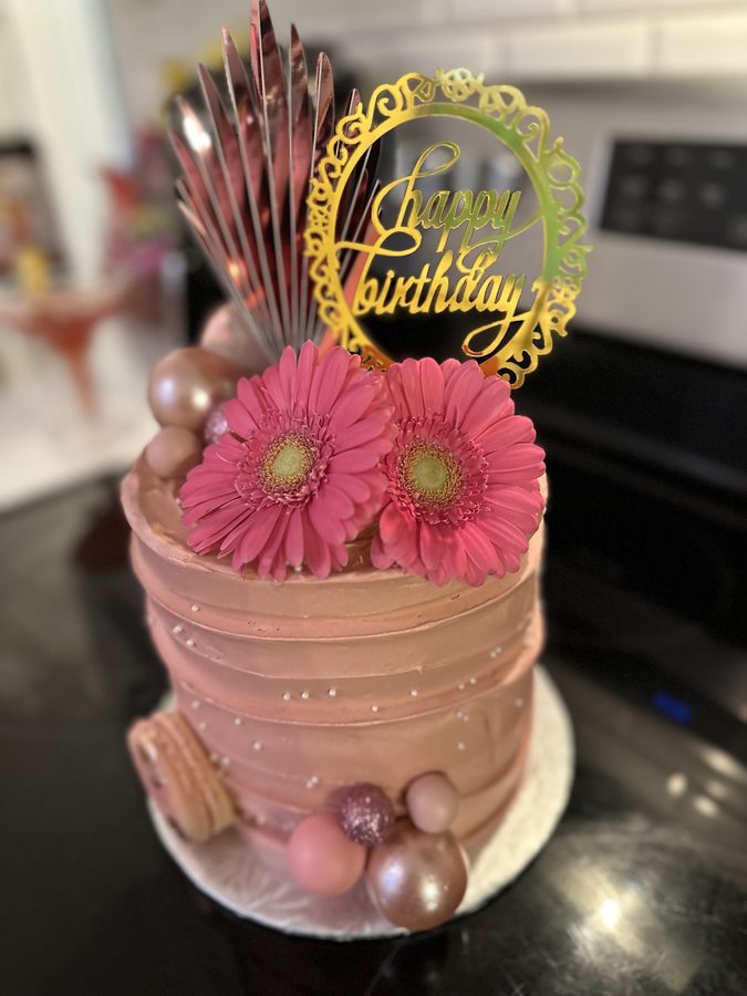 Rose-gold buttercream cake with fresh gerbera daisies and macarons