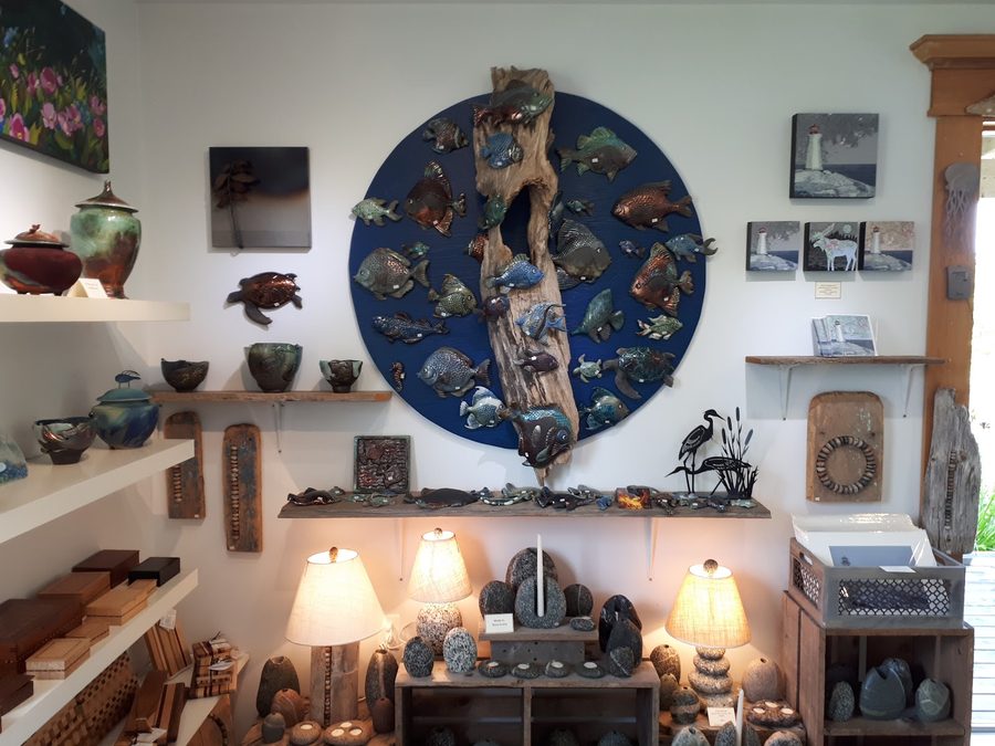 Handmade metal fish-sculpture wall art alongside pottery