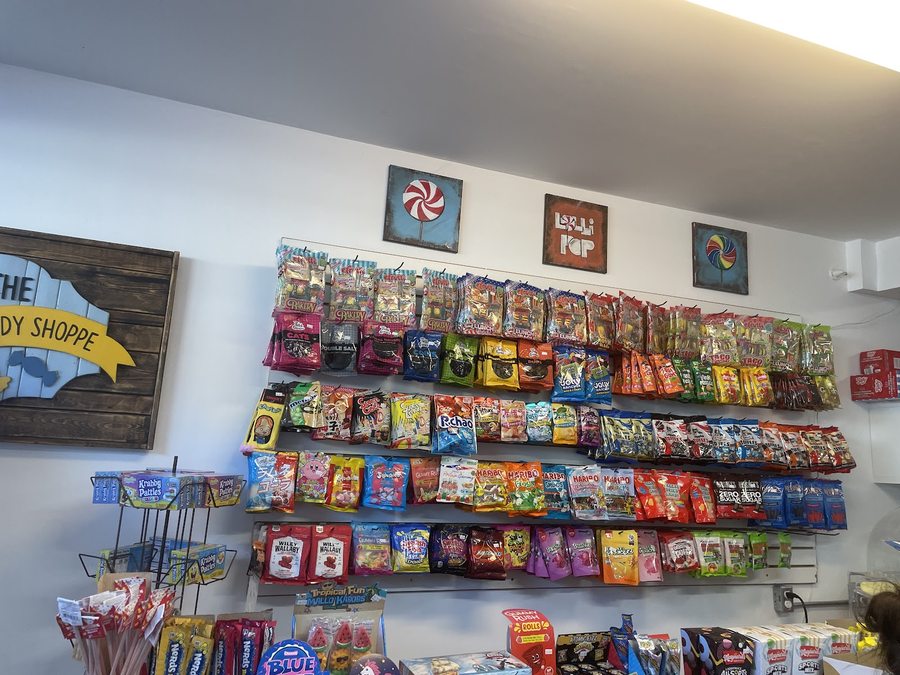 Shelf rails packed wall to wall with bags and boxes of novelty candy, gummies, chocolate bars and lollipops inside The Rideau Candy Shoppe.