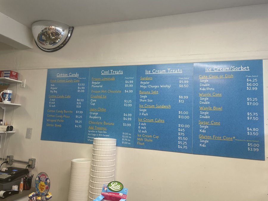 The shop's four blue menu boards on a cream wall — Cotton Candy, Cool Treats, Ice Cream Treats and Ice Cream and Sorbet — each with a gold underlined heading and white items with prices.