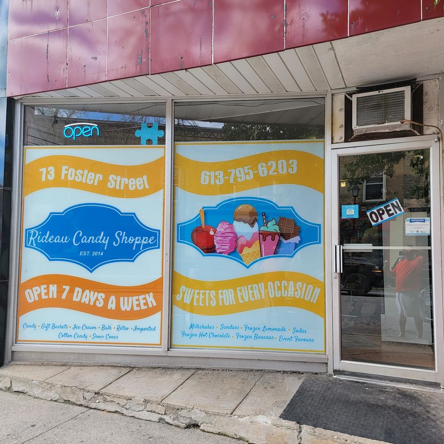 The shop's window decal reading Rideau Candy Shoppe, EST. 2014, with OPEN 7 DAYS A WEEK and a lit blue OPEN sign in the glass.