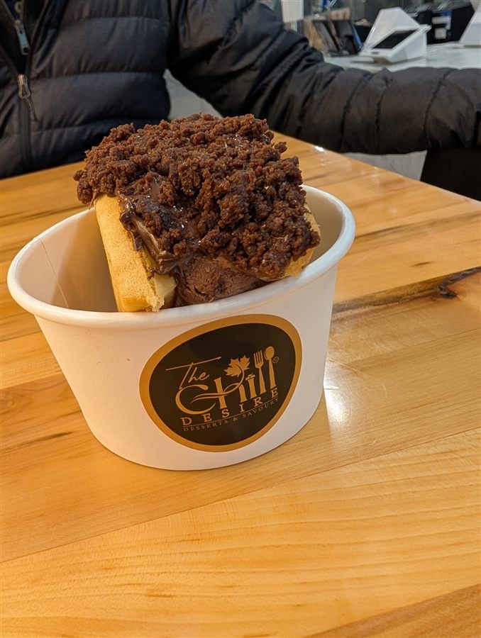 A customer holding a branded The Chill Desire cup with a waffle-and-ice-cream dessert