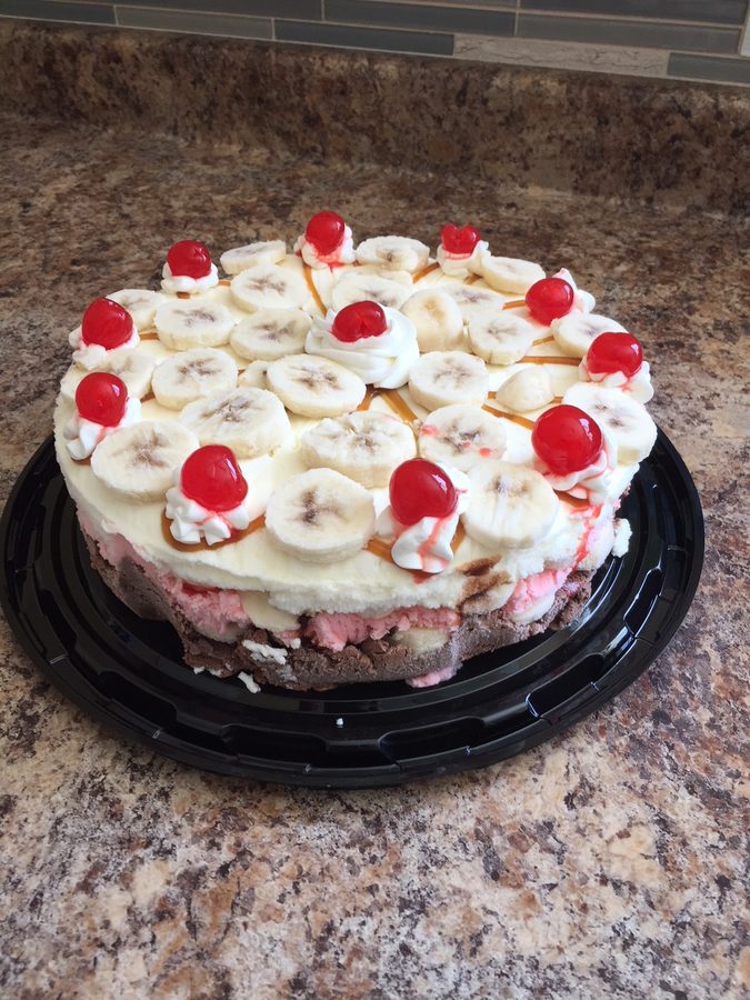 A banana split ice cream cake with banana slices, cherries and caramel
