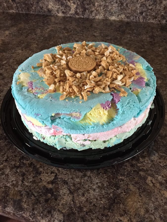 A pastel rainbow ice cream cake topped with cookie crumble