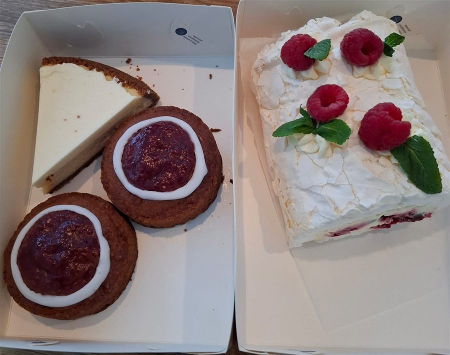 Avattu mukaanottolaatikko: juustokakkua, marmeladipikkuleipiä ja vadelmarullaa.