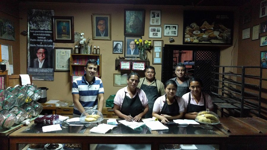 El equipo de la panadería junto al mostrador, bajo el rótulo de las cuatro generaciones