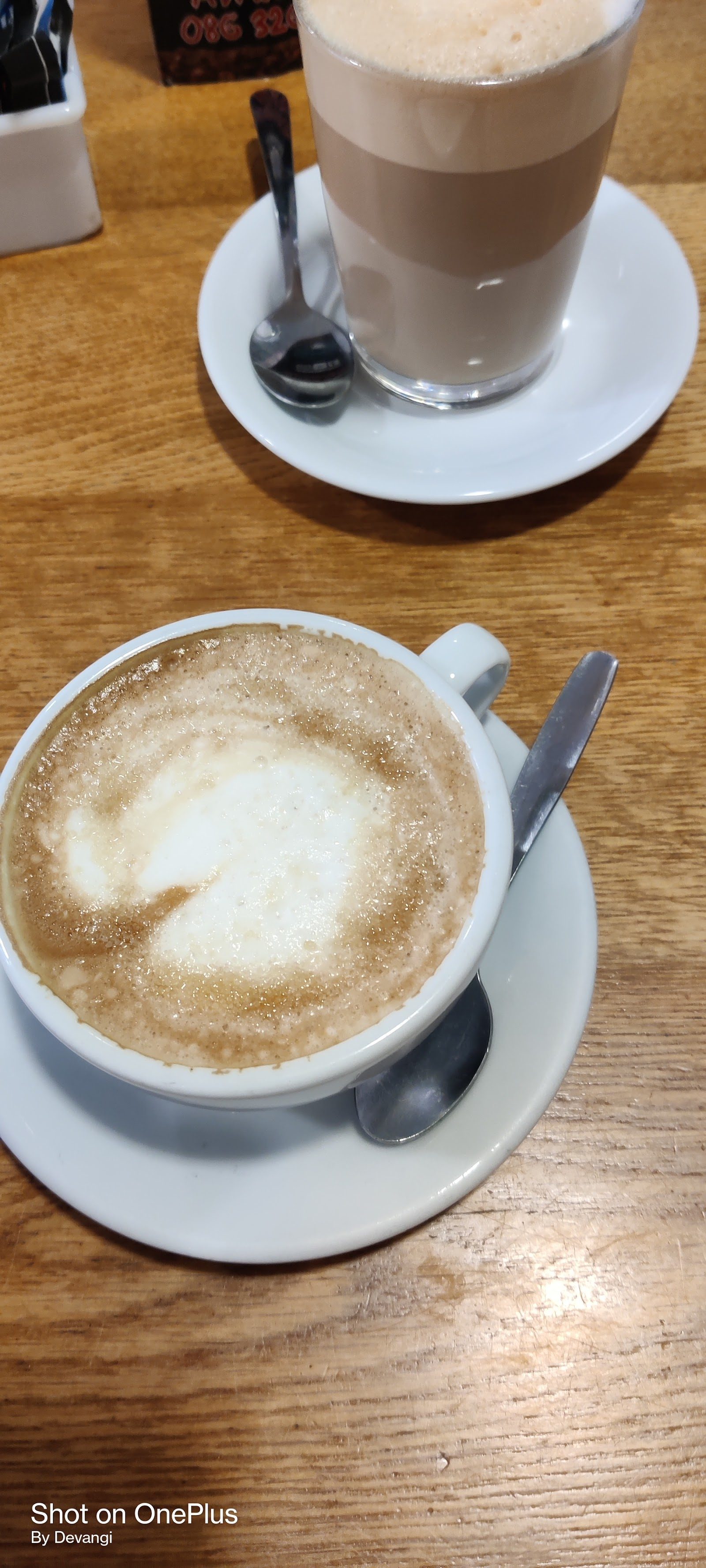 A latte in a glass and a frothy cappuccino at Goodies Coffee House