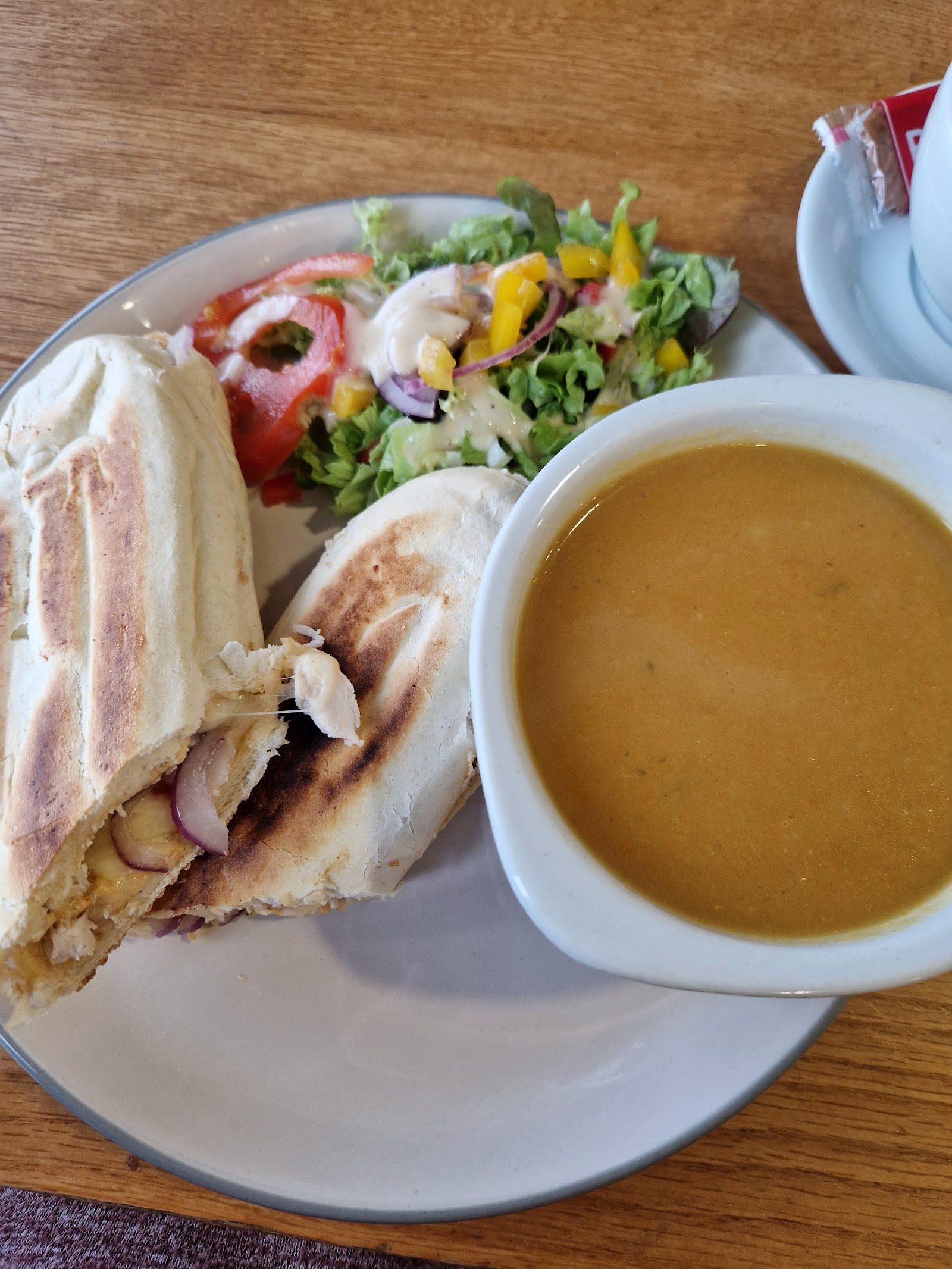 A toasted wrap with a bowl of homemade soup and a side salad