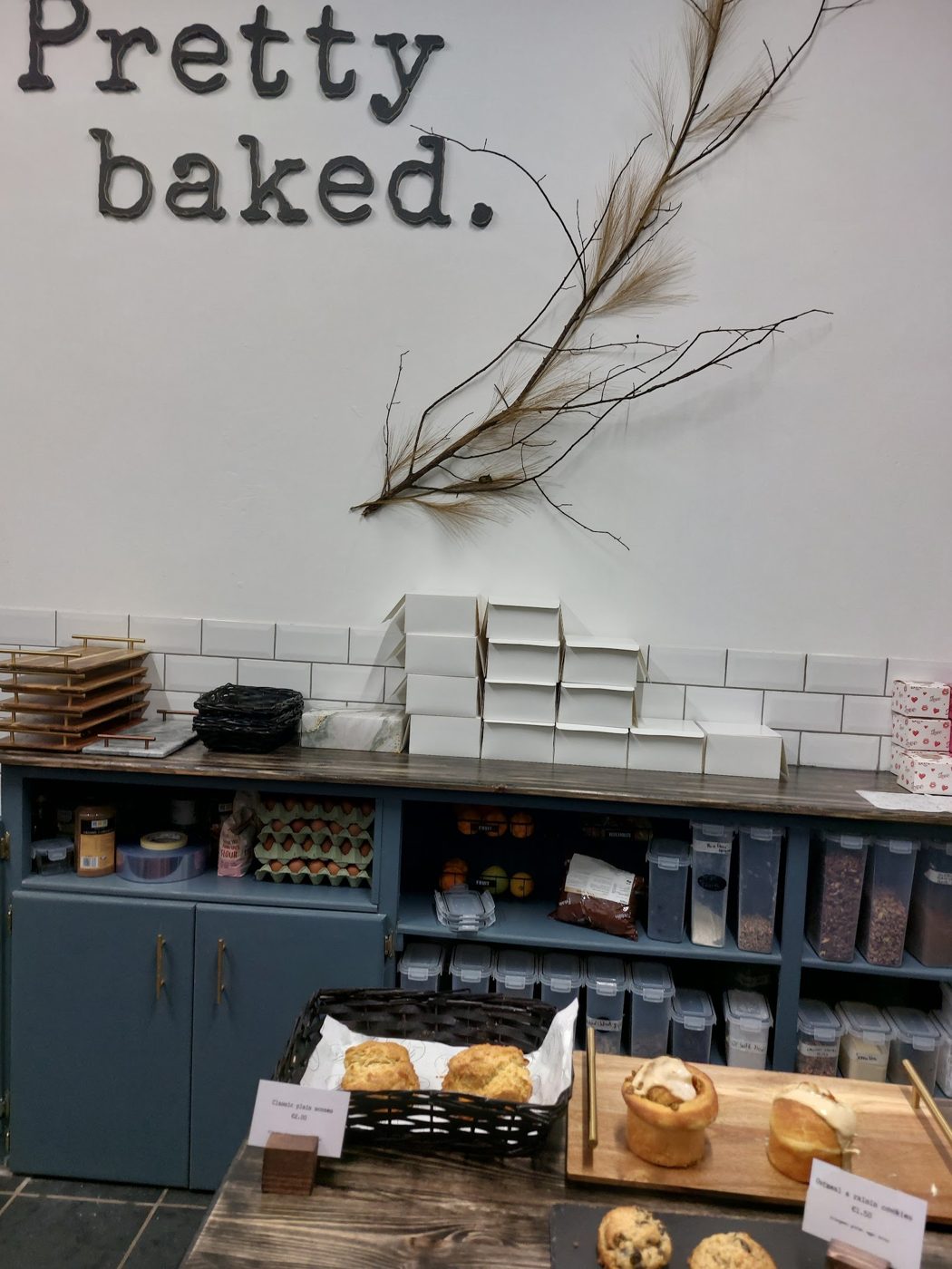 The Pretty Baked counter with scones, cookies and the hand-lettered Pretty Baked sign on the wall
