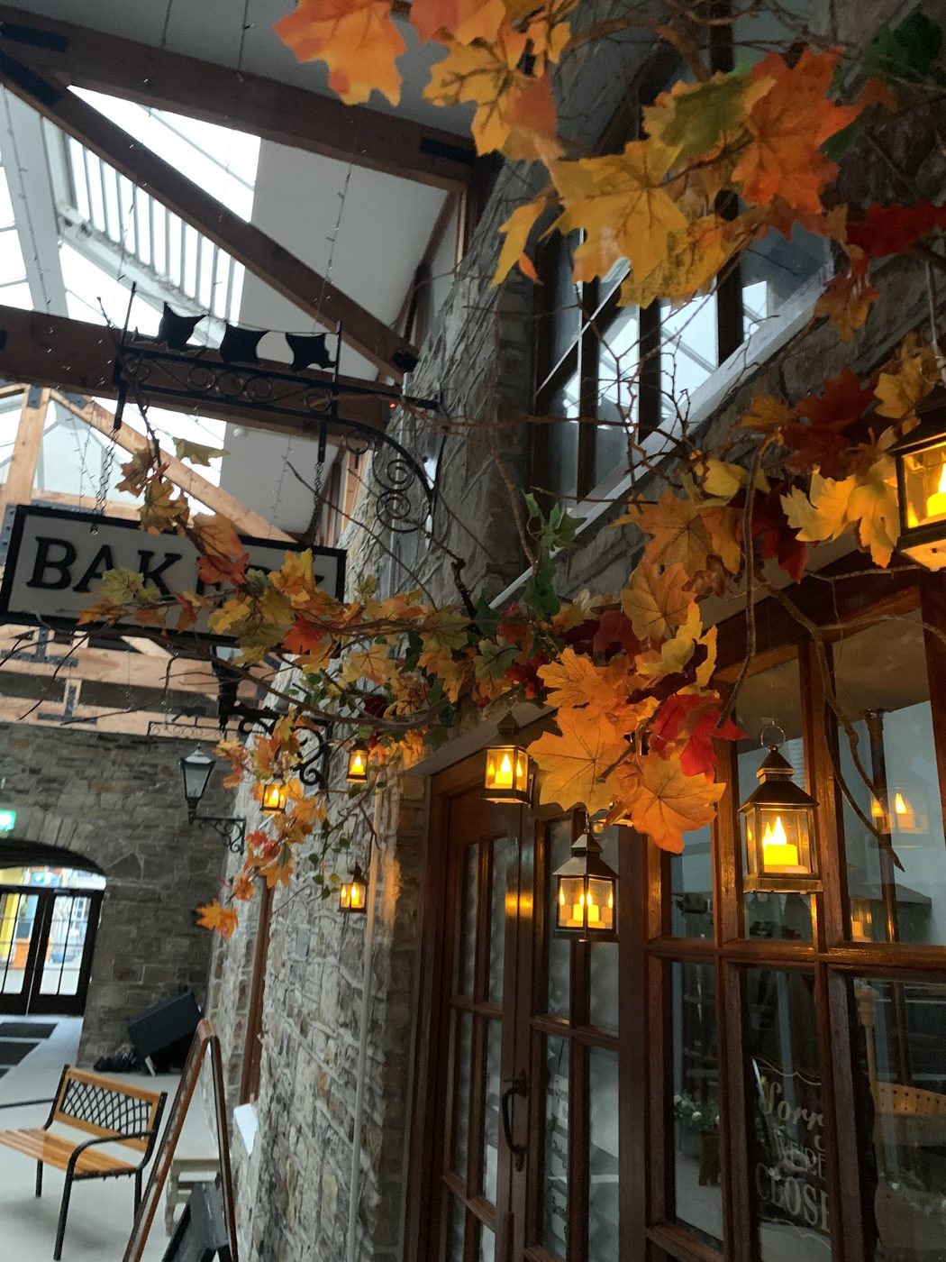Inside Millcourt Mews — exposed stone, timber beams, hanging lanterns and a bakery sign