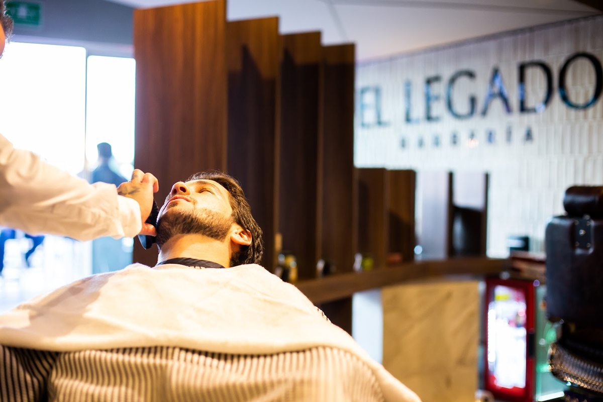 Servicio de barbería con la marca El Legado visible al fondo