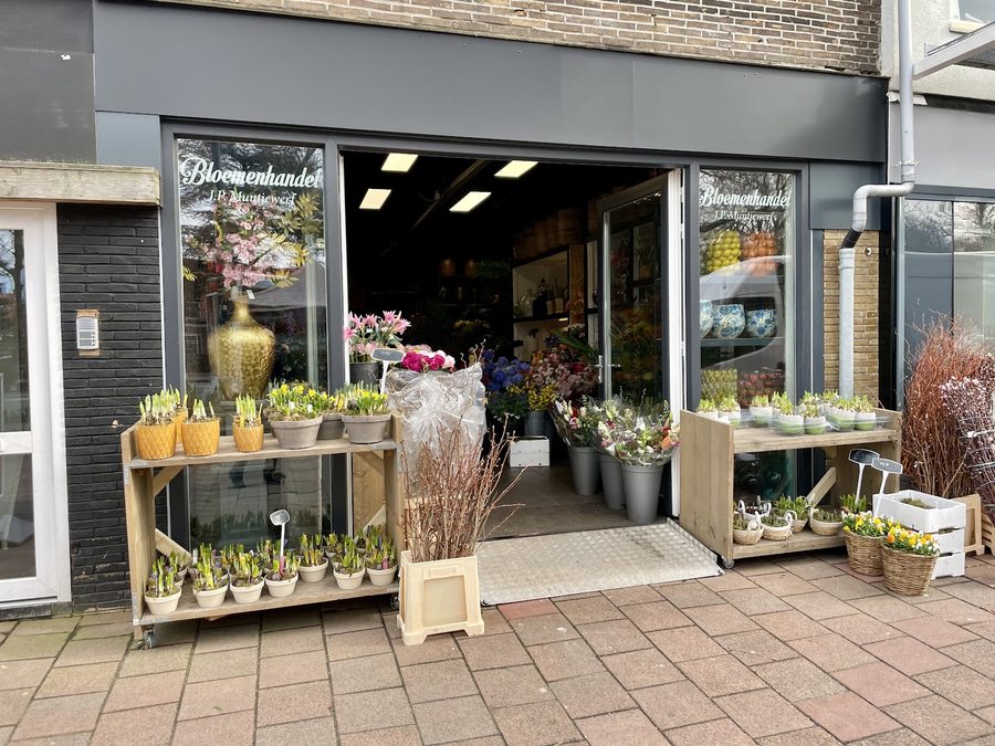 De winkelpui van Bloemenhandel J.P. Muntjewerf met potbollen, bloembuckets en Delfts aardewerk