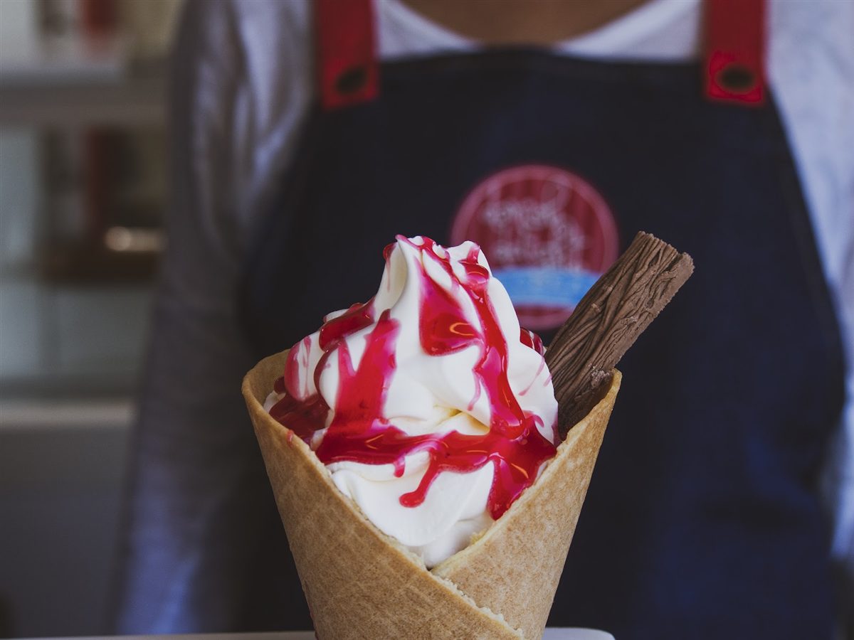 Hand-dipped waffle cone with soft-serve and raspberry sauce