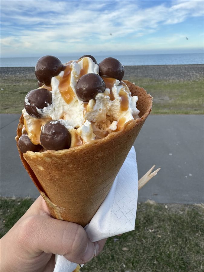 Ice cream cone held up against Napier's Marine Parade waterfront