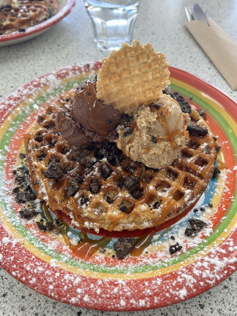 A hot Belgium waffle sundae with three scoops, powdered sugar and caramel sauce