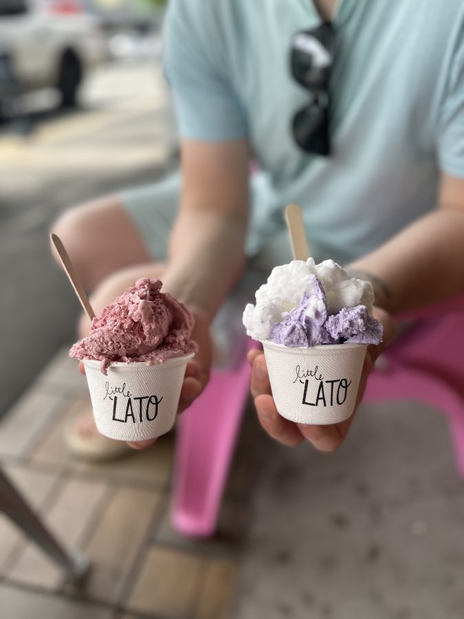 A customer holding two little cups of gelato outside Ice ice Baby