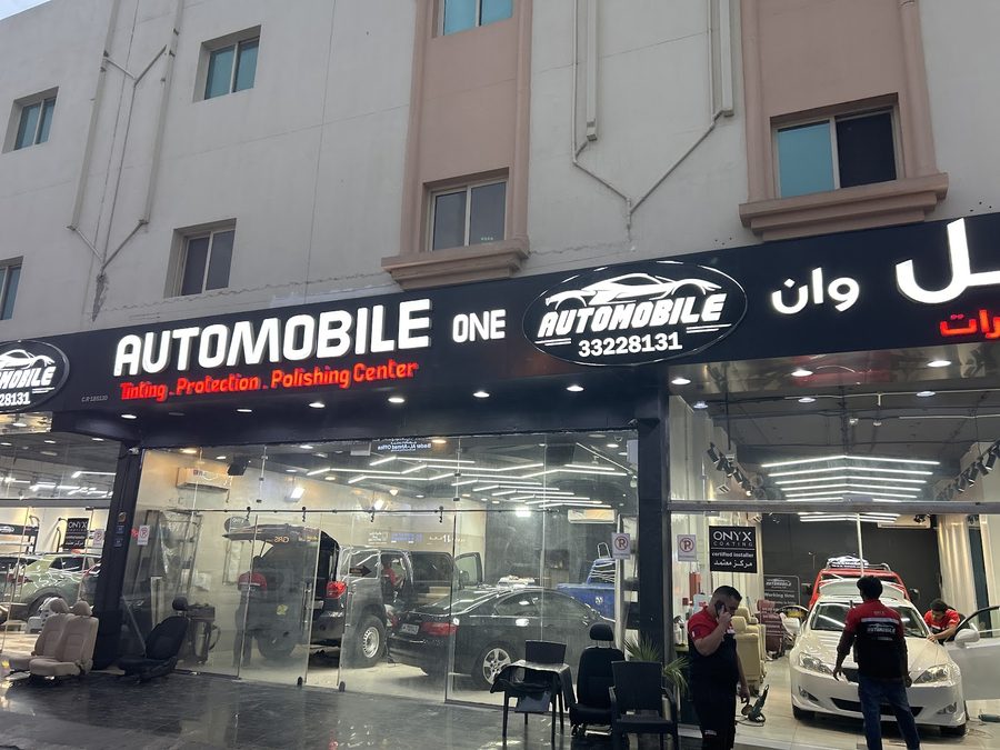 Daytime exterior of Automobile Car Center with staff servicing customer cars.
