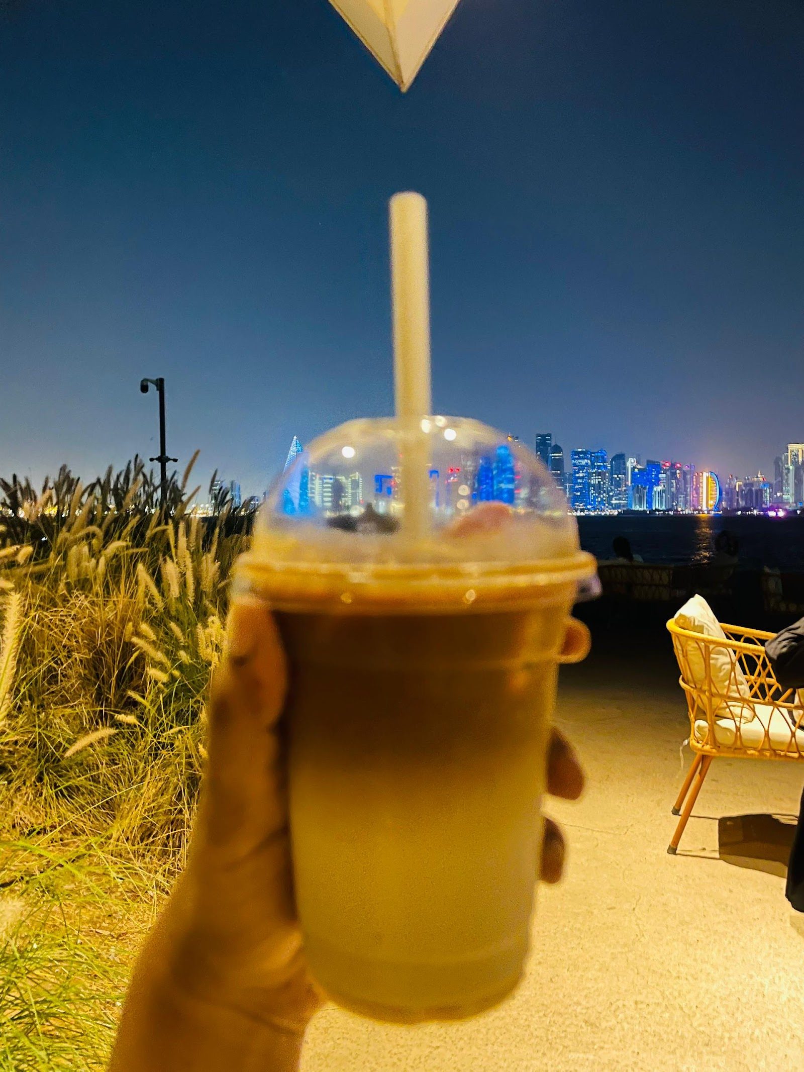 كأس كرك مثلج أمام أفق الدوحة · Iced karak against the Doha skyline