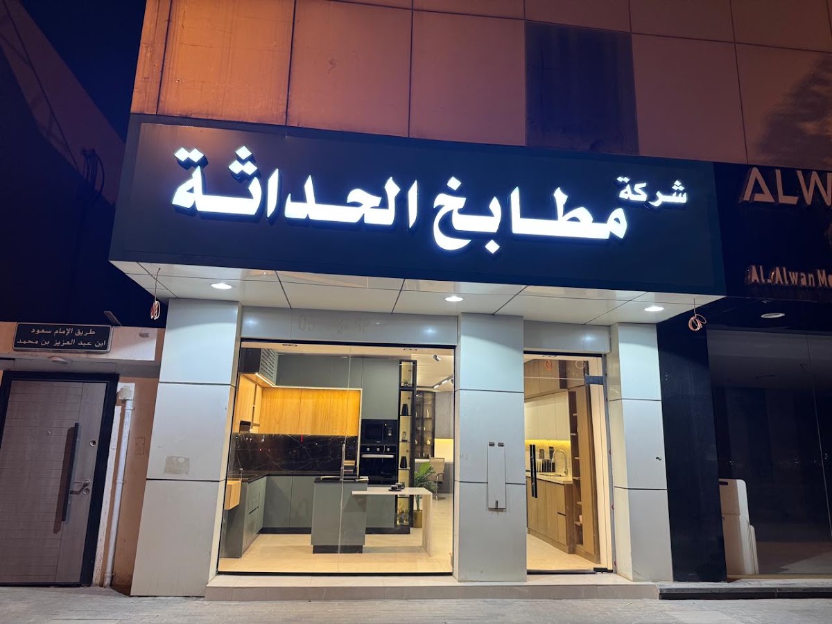 واجهة معرض مطابخ الحداثة ليلاً، ولوحة الاسم المضاءة فوق الواجهة الزجاجية والمطبخ المعروض في الداخل