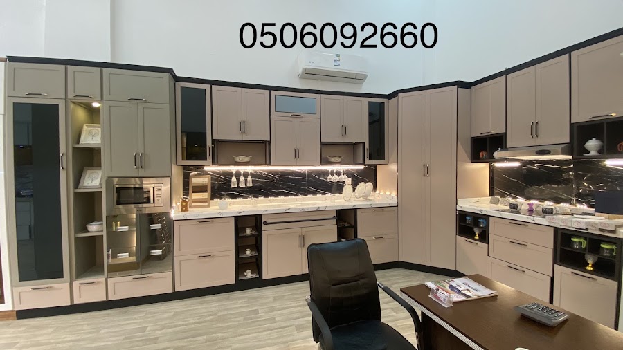 مطبخ بيج بإطارات سوداء وخلفية رخام أسود بعروق بيضاء وسطح رخامي فاتح