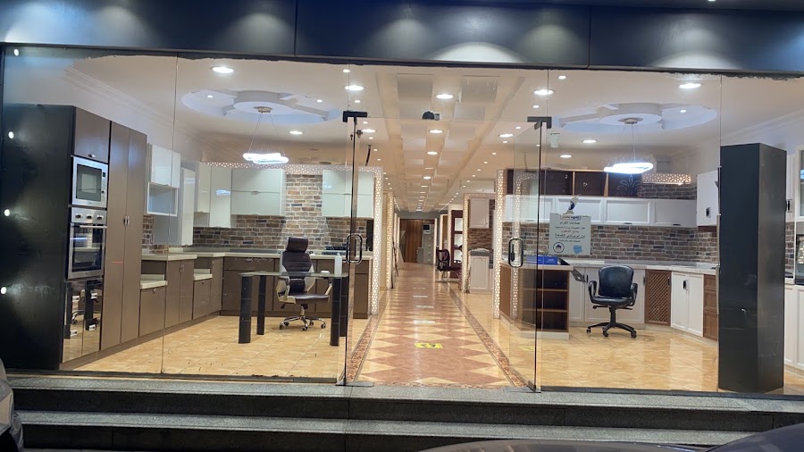 صالة عرض بواجهة زجاجية فيها نماذج مطابخ على جانبي ممر طويل