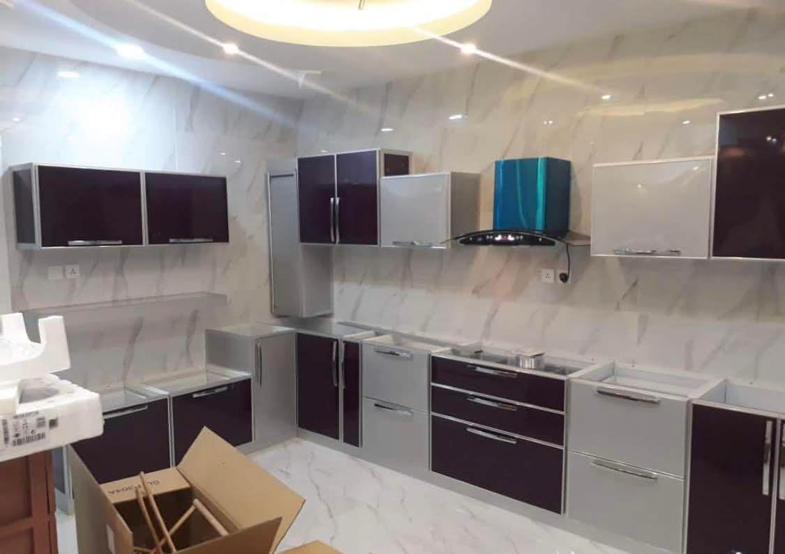مطبخ ألمنيوم بأبواب باذنجانية لامعة وأخرى بيضاء داخل إطارات فضية، أثناء التركيب