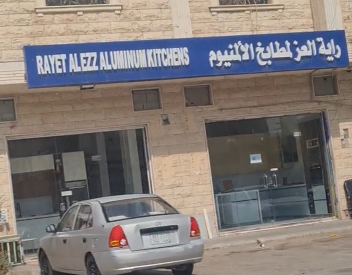واجهة محل راية العز بلوحته الزرقاء على مبنى من الحجر