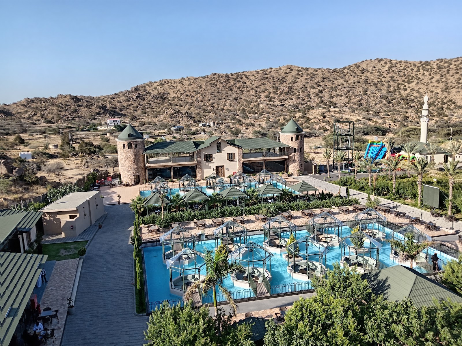Aerial view of Baz resort with family pools and the Al Shafa mountains
