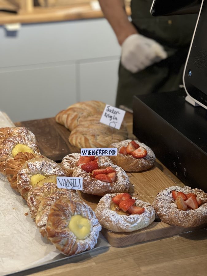 Närbild på bakverk i disken med handskrivna namnskyltar.