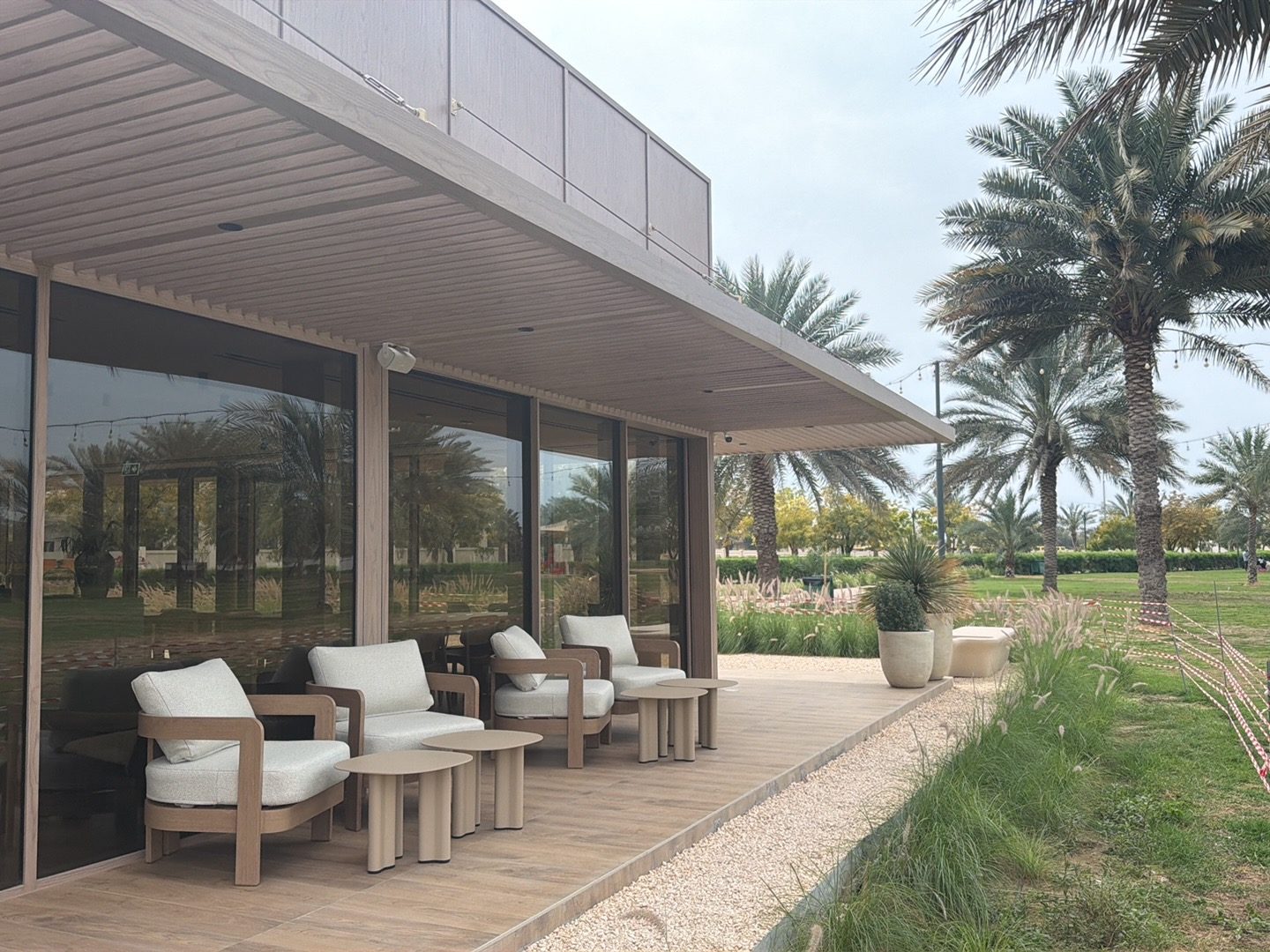 Outdoor terrace with cream lounge chairs, a wood deck and date palms in Al Safiya Park