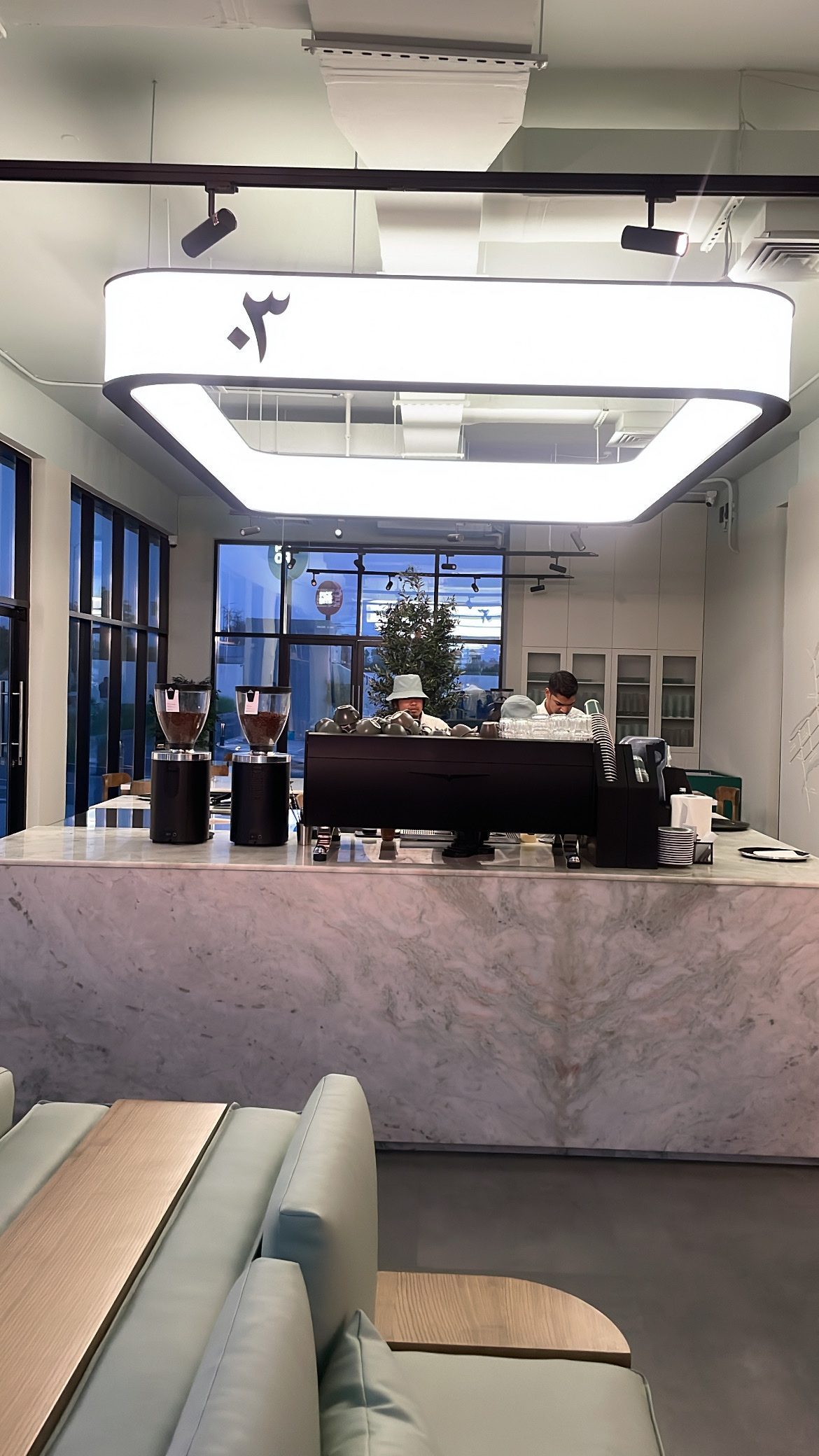 The marble coffee bar at Qahwa03 with the signature ٣ light fixture