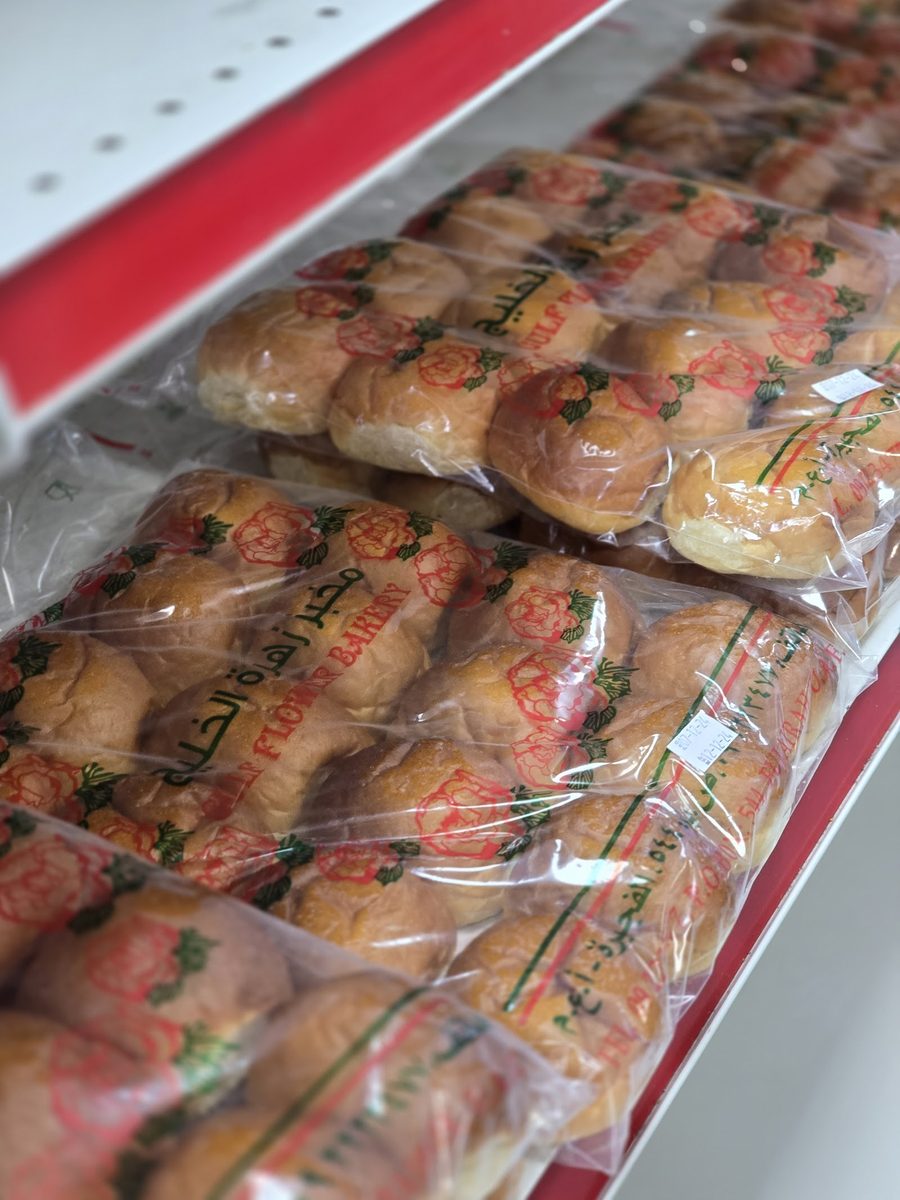 أرغفة ذهبية طازجة بأكياس مخبز زهرة الخليج المطبوعة بالوردة / Fresh golden buns bagged with Gulf Flower Bakery's rose-print packaging
