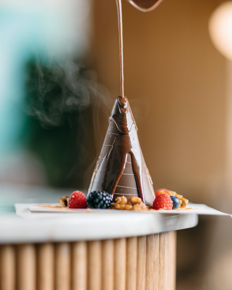 Chocolate cone dessert with fresh berries and warm chocolate pour