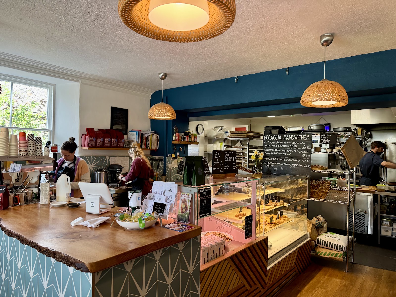 Lucia's interior with a teal feature wall, wicker lights and a wooden counter