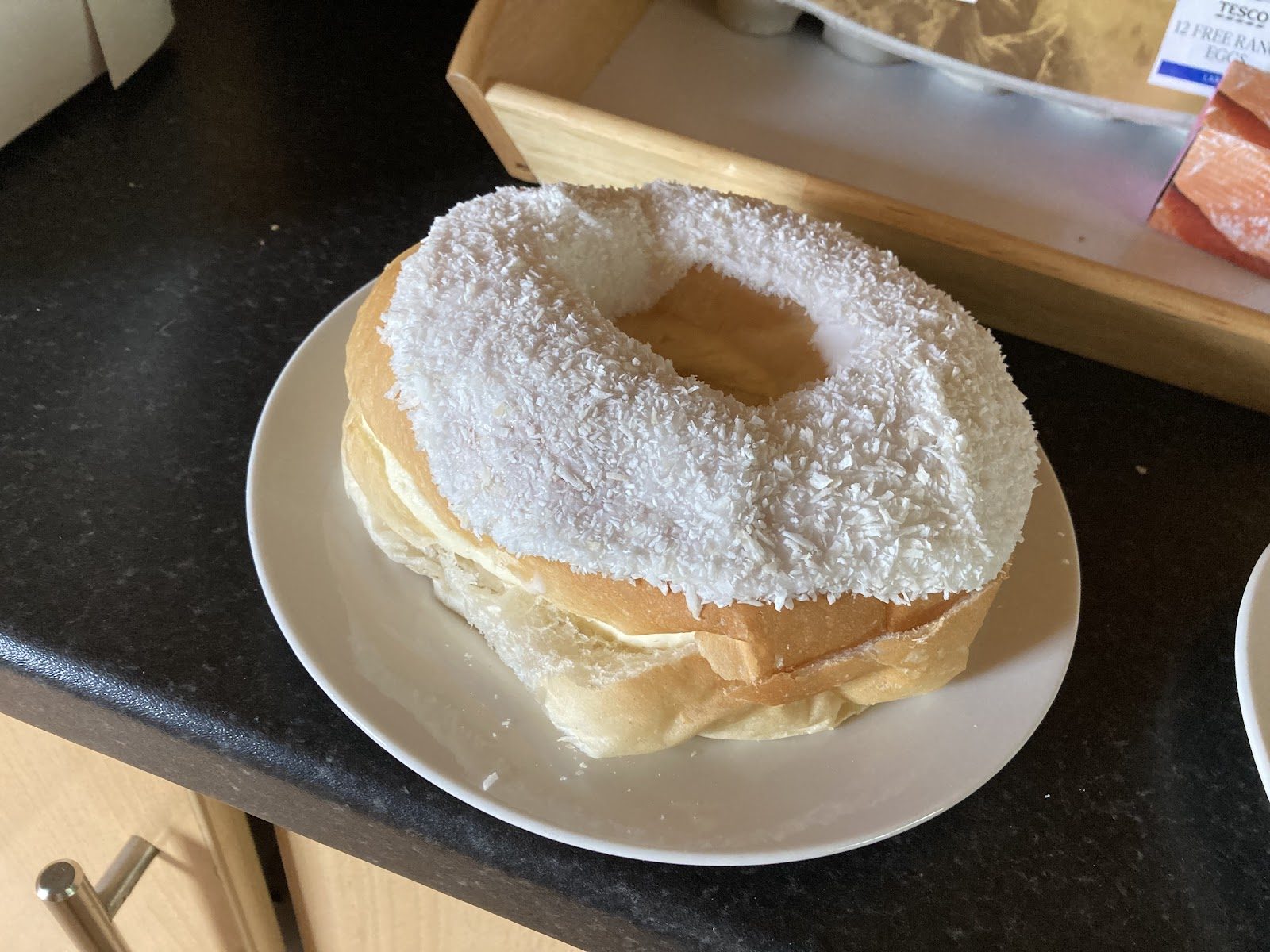 A soft coconut-dusted snowball ring (Paris bun) on a plate at Paul Jones Bakery