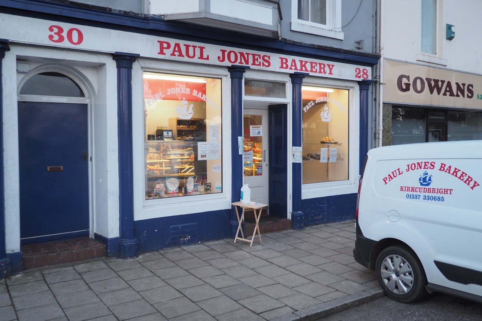 The navy-and-white shopfront of Paul Jones Bakery on St Cuthbert's Street, Kirkcudbright, with red lettering and the branded delivery van