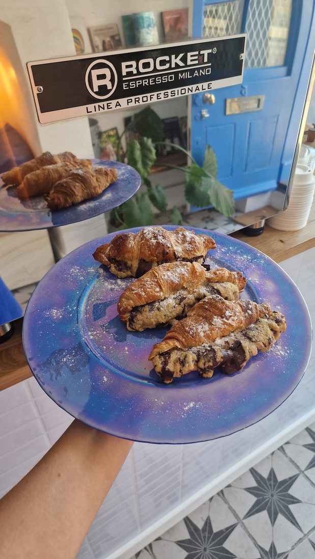 Sugar-dusted vegan chocolate croissants on an iridescent blue plate.