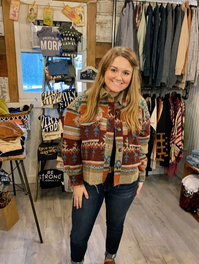 A customer trying on a jacket inside Brave Hazel Boutique