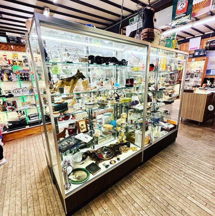 A lit glass case of vintage figurines and glassware