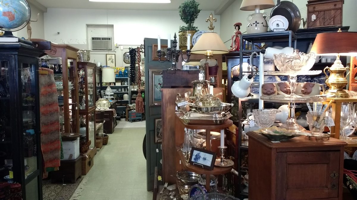Aisles of curated cabinets, silver, glassware and lamps inside Off Main Antiques