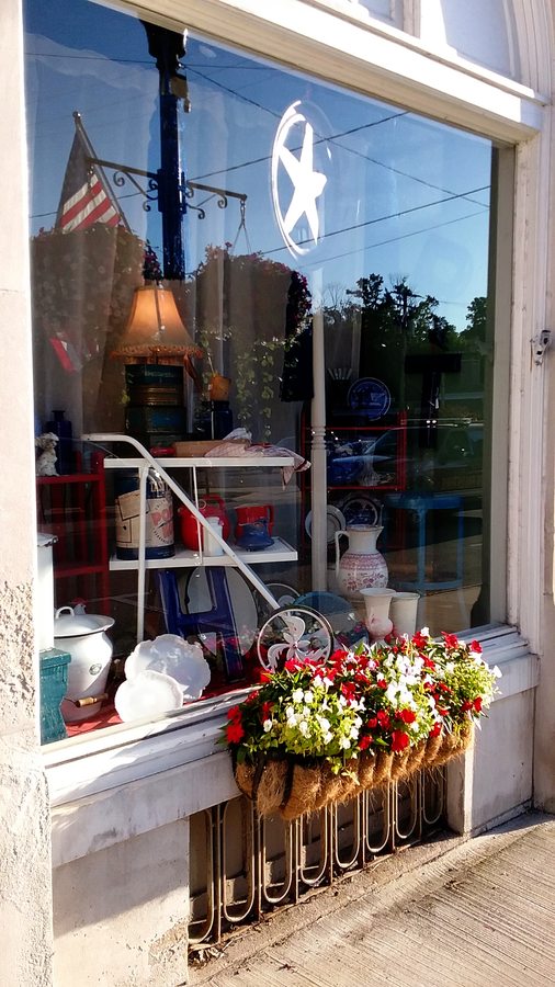 A seasonal shop window arranged with florals and vintage pieces