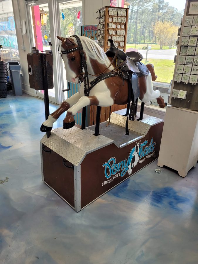 A coin-operated paint-pony ride inside Pony Tails, branded with the shop's logo
