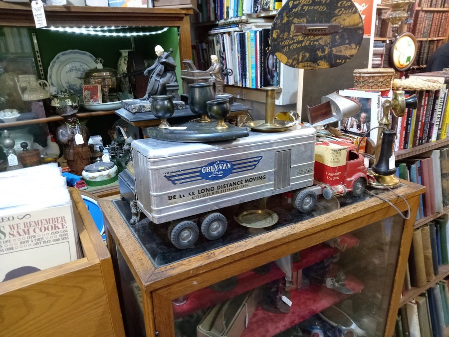 A vintage toy moving truck, brass candlesticks and an antique candlestick telephone on display